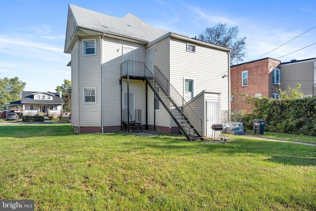 rear view of house featuring stairs, a lawn, a balcony, and entry steps