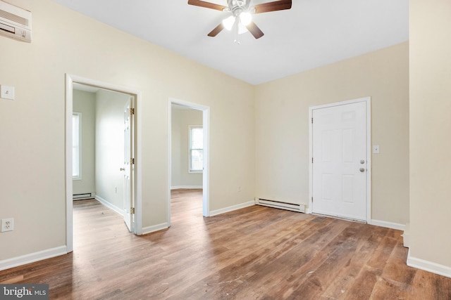 spare room featuring a baseboard radiator, baseboards, and wood finished floors