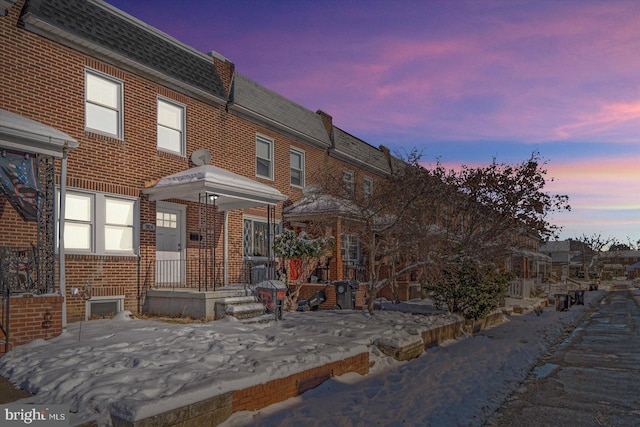 view of front of property with brick siding, mansard roof, and a shingled roof