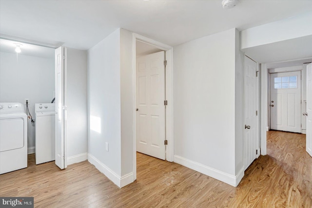 washroom with laundry area, baseboards, light wood finished floors, and washing machine and clothes dryer