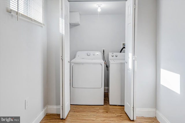 laundry area featuring laundry area, washing machine and dryer, baseboards, and light wood-style floors