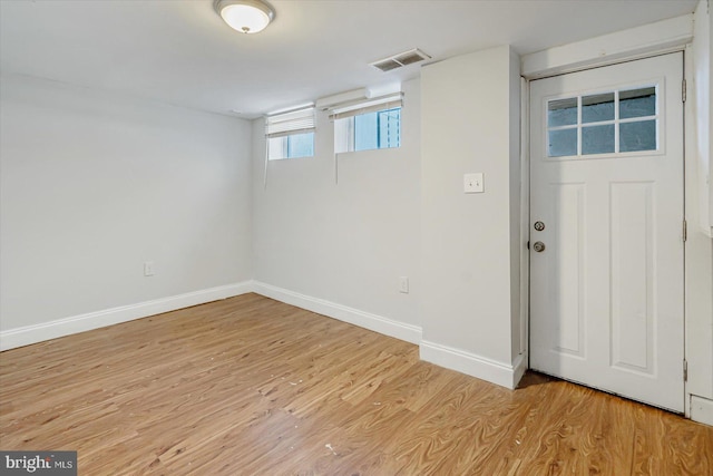 basement featuring light wood finished floors, baseboards, and visible vents