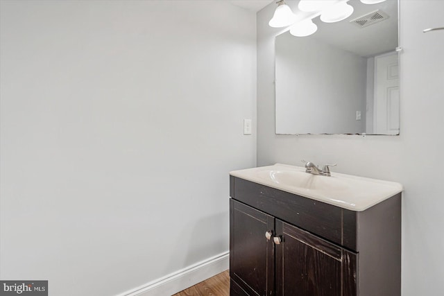 bathroom with vanity, wood finished floors, visible vents, and baseboards