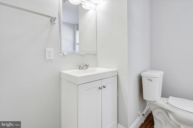 bathroom with toilet, baseboards, and vanity