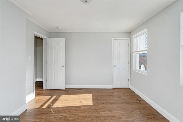 spare room featuring wood finished floors and baseboards