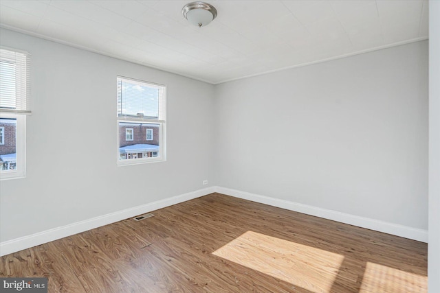 spare room with visible vents, baseboards, and wood finished floors