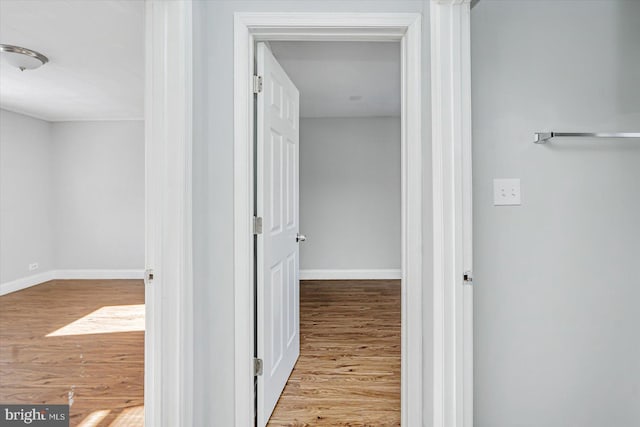 hall with baseboards and wood finished floors