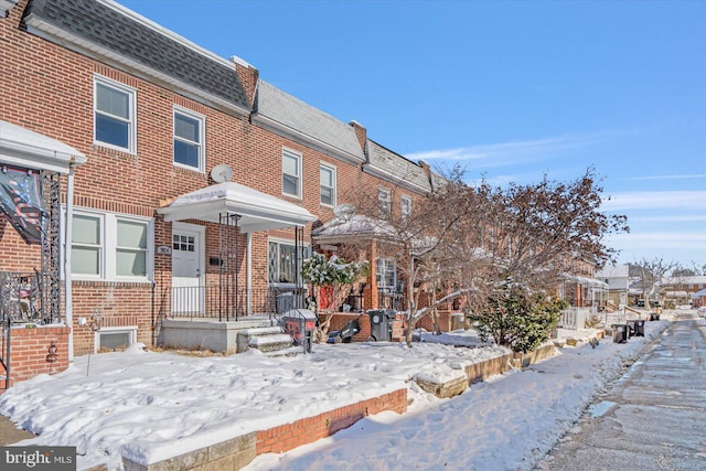 townhome / multi-family property featuring roof with shingles, a residential view, mansard roof, and brick siding