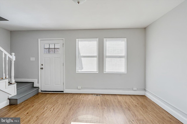 entryway featuring light wood-style flooring, baseboards, and stairs