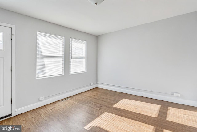 unfurnished room with baseboards, visible vents, and wood finished floors