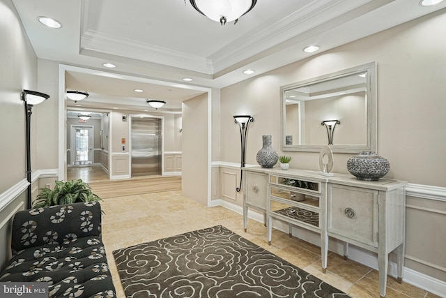 bathroom with a raised ceiling, a decorative wall, ornamental molding, elevator, and wainscoting