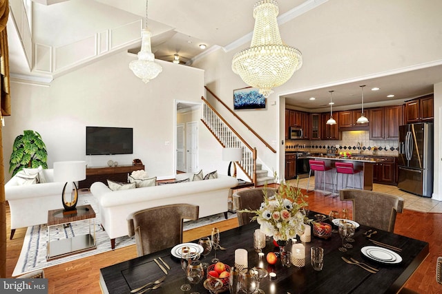 dining room with stairway, a chandelier, light wood finished floors, and ornamental molding