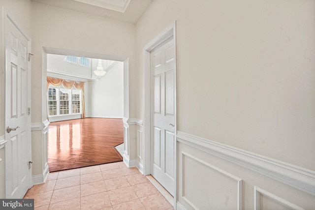 corridor with a wainscoted wall and light tile patterned floors