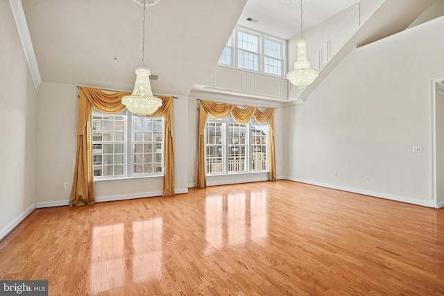 unfurnished living room featuring a chandelier, wood finished floors, and a wealth of natural light