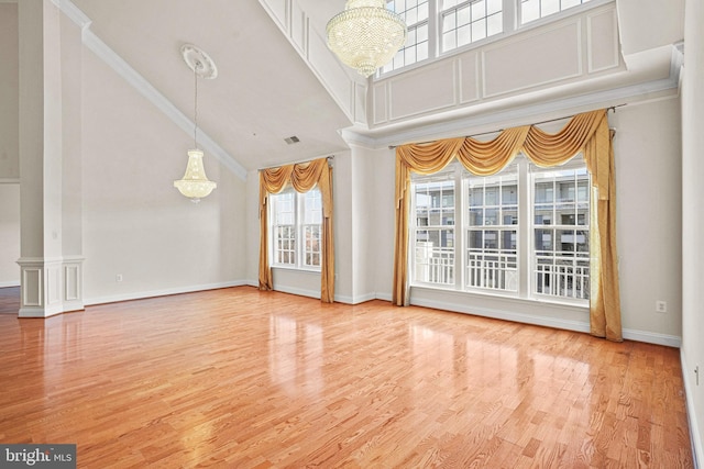 unfurnished living room featuring a chandelier, high vaulted ceiling, wood finished floors, and crown molding