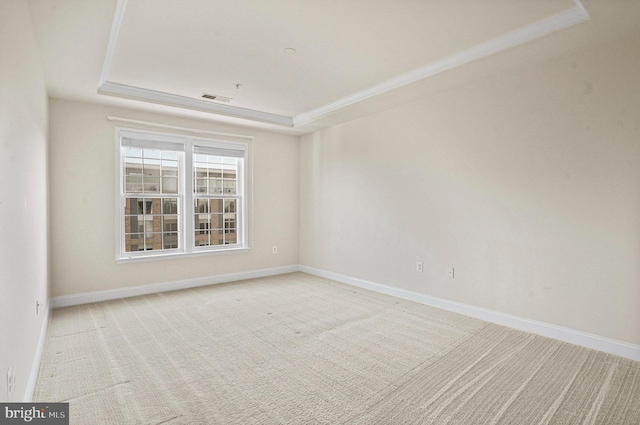 carpeted empty room with a tray ceiling, visible vents, and baseboards