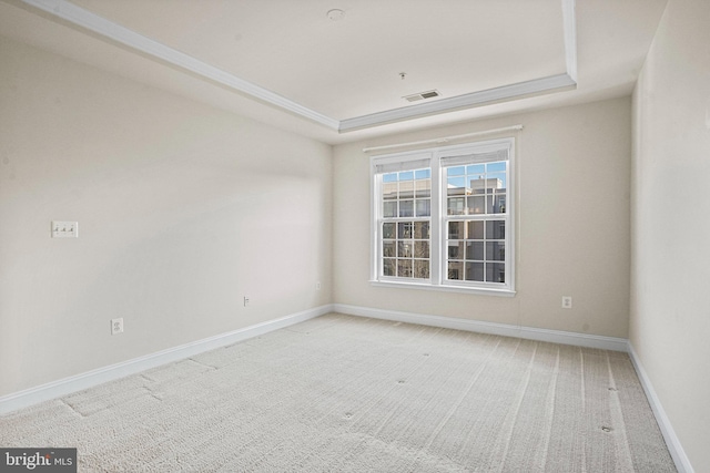 spare room featuring carpet, visible vents, and a raised ceiling