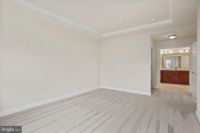 unfurnished room with a raised ceiling, light carpet, crown molding, and baseboards