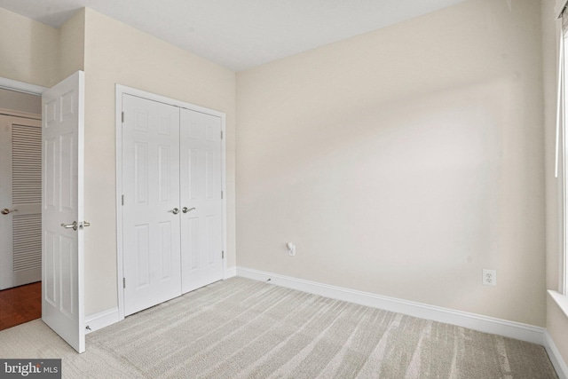 unfurnished bedroom with baseboards, a closet, and light colored carpet