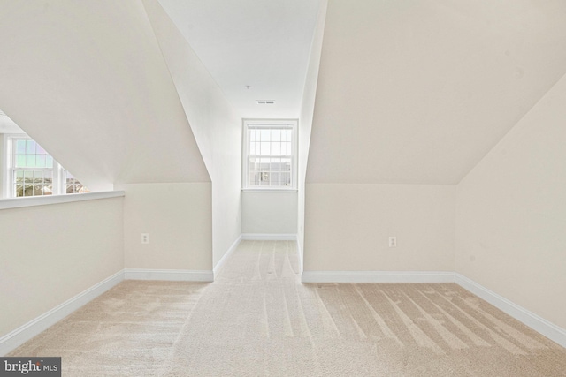 additional living space with carpet, visible vents, vaulted ceiling, and baseboards