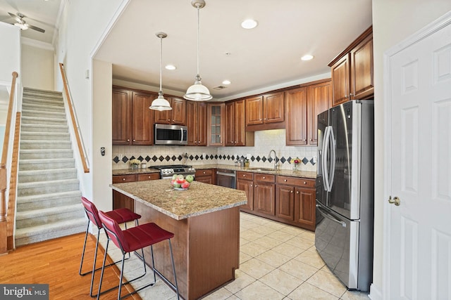 kitchen featuring a breakfast bar, backsplash, stainless steel appliances, and a sink