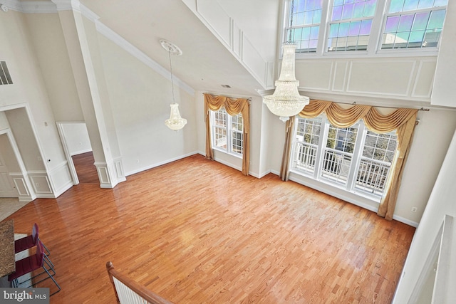 living room with a chandelier, high vaulted ceiling, wood finished floors, and crown molding