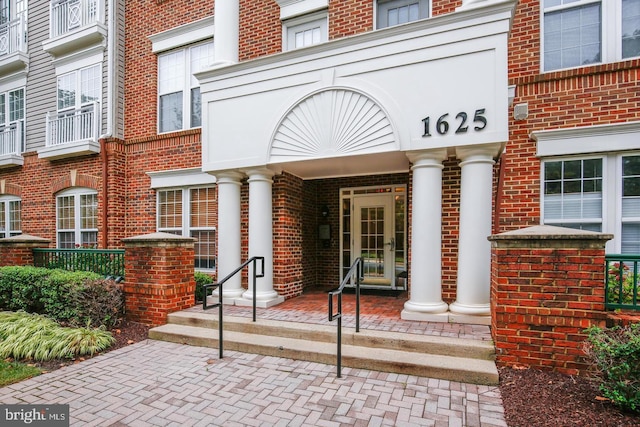 view of exterior entry featuring covered porch, french doors, and brick siding