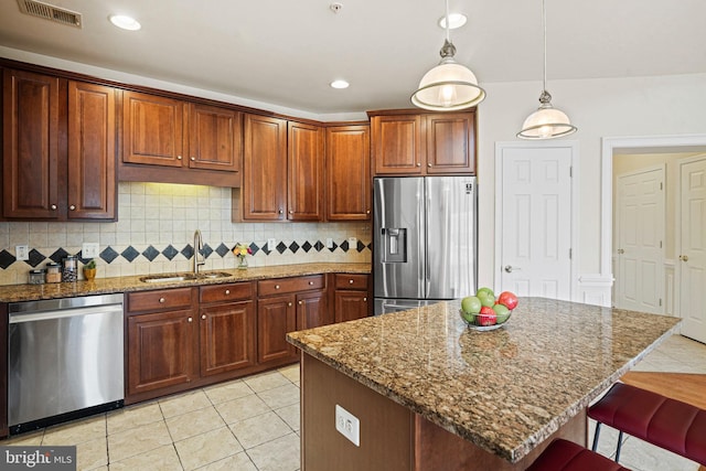 kitchen with tasteful backsplash, visible vents, appliances with stainless steel finishes, a sink, and a kitchen bar