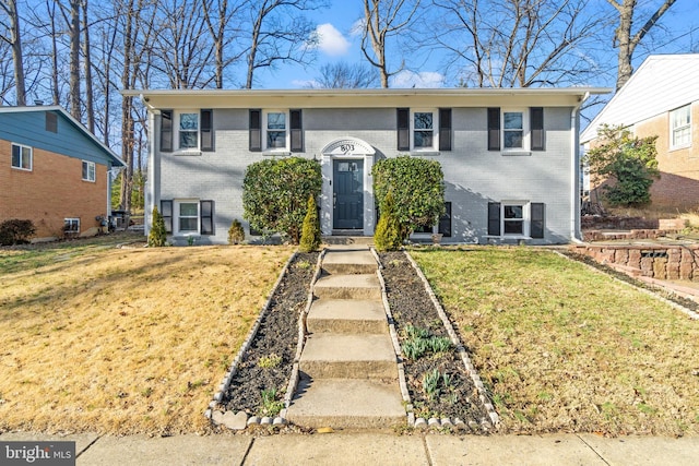 raised ranch featuring brick siding and a front lawn