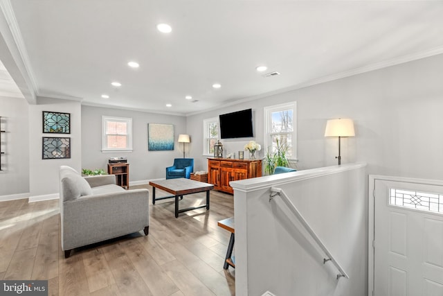 living room featuring light wood-style floors, visible vents, and crown molding