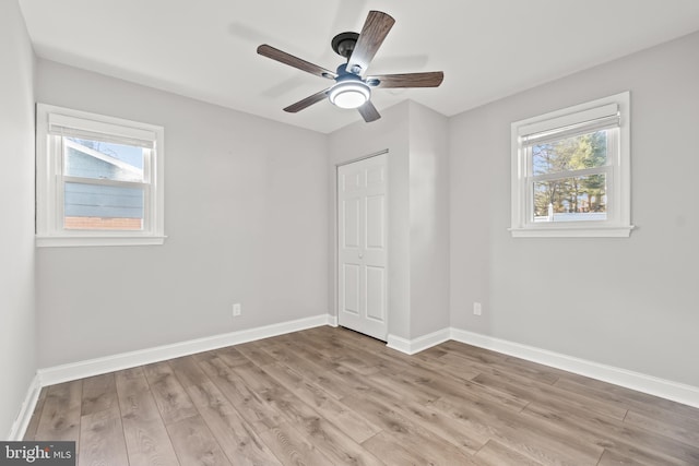 unfurnished bedroom featuring ceiling fan, light wood finished floors, a closet, and baseboards