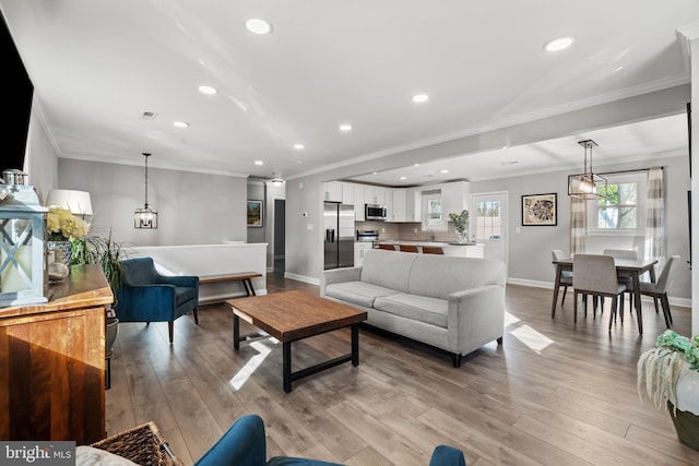 living room featuring light wood-style floors, baseboards, and ornamental molding