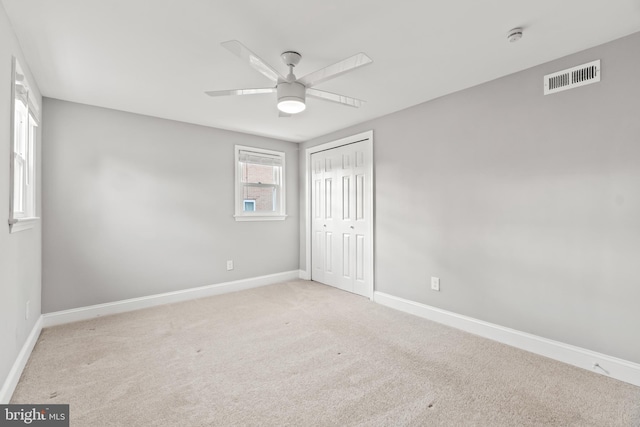 unfurnished bedroom with carpet, a closet, visible vents, a ceiling fan, and baseboards