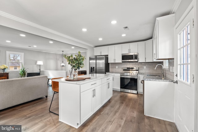 kitchen with open floor plan, appliances with stainless steel finishes, light wood-type flooring, and a sink