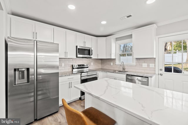 kitchen with stainless steel appliances, a sink, visible vents, and white cabinetry