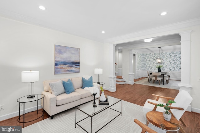 living room featuring ornamental molding, wainscoting, decorative columns, and wood finished floors