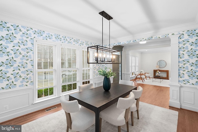 dining space with wallpapered walls, visible vents, a wainscoted wall, and ornate columns