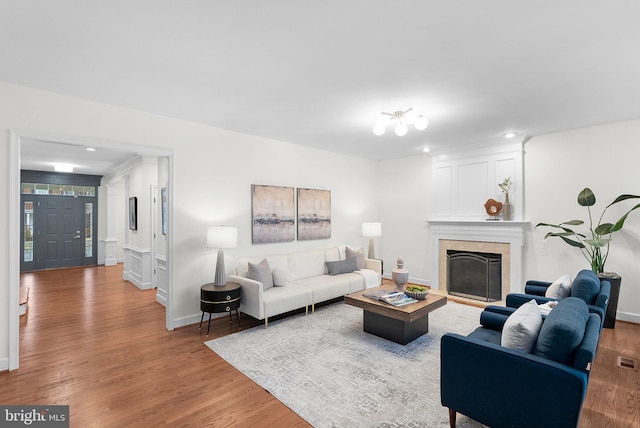 living area with visible vents, wood finished floors, a high end fireplace, and baseboards