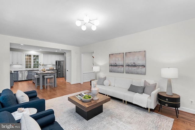 living room with recessed lighting, an inviting chandelier, baseboards, and wood finished floors