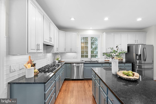 kitchen with white cabinets, backsplash, stainless steel appliances, and a sink