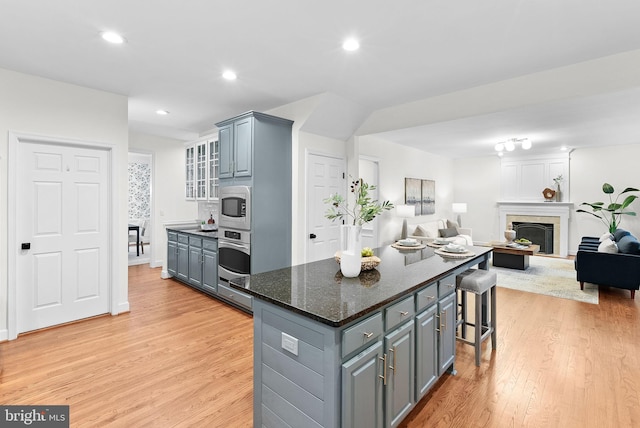 kitchen featuring light wood finished floors, stainless steel oven, and gray cabinetry