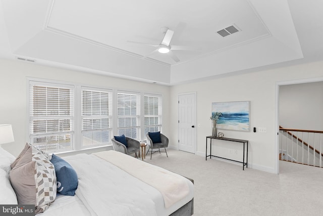 bedroom featuring a tray ceiling, light colored carpet, visible vents, and baseboards