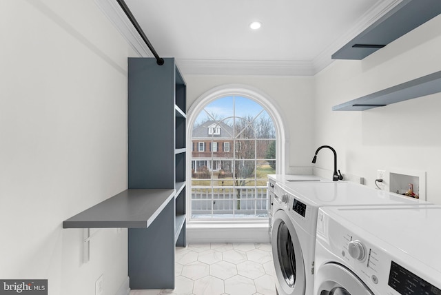 washroom featuring crown molding, light tile patterned floors, a sink, washer and dryer, and laundry area