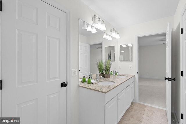 bathroom with double vanity, baseboards, and a sink