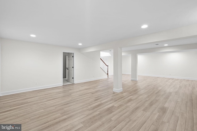 finished below grade area featuring light wood finished floors, stairway, and recessed lighting