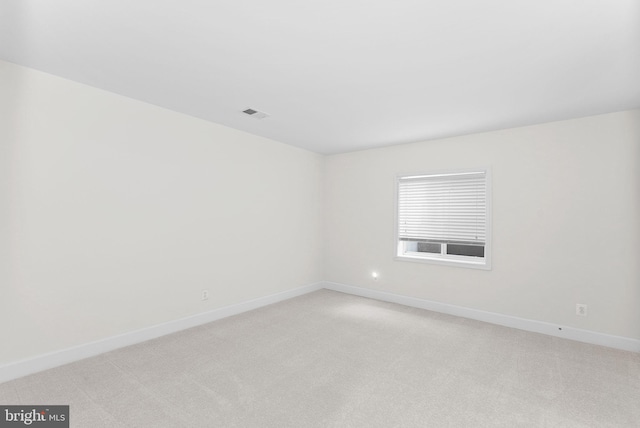 empty room with baseboards, visible vents, and light colored carpet