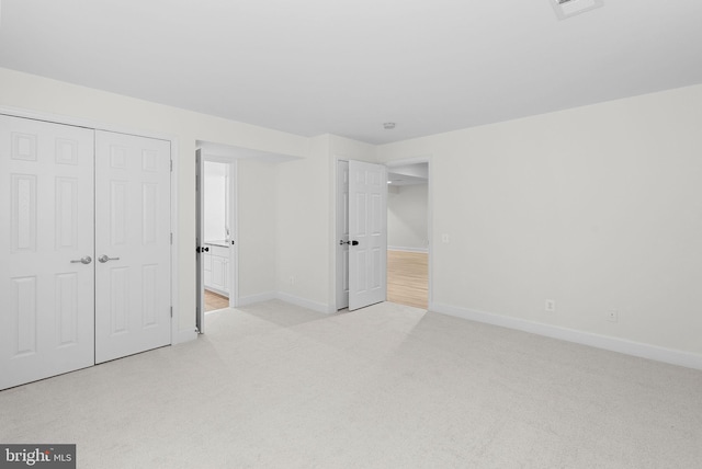 unfurnished bedroom with carpet floors, connected bathroom, baseboards, and a closet