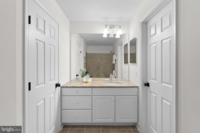 bathroom featuring tile patterned flooring, tiled shower, and vanity