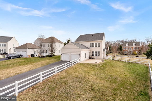 back of house featuring a residential view, fence, an outbuilding, and a yard