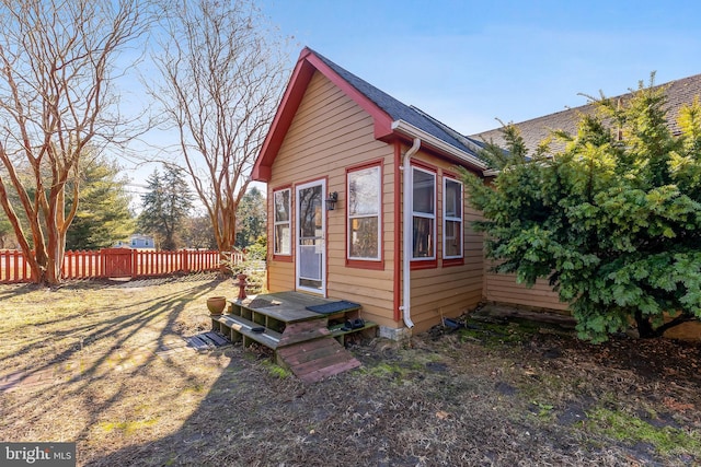 view of side of property featuring roof with shingles and fence